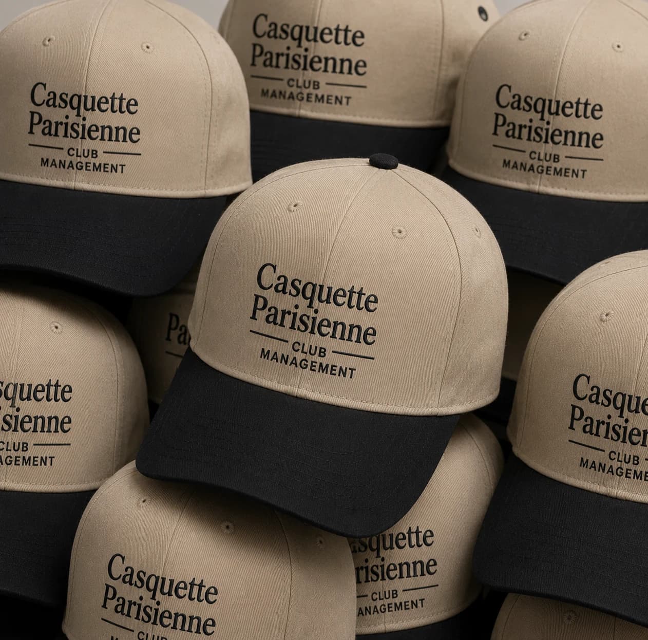 Série de casquettes beige et noir brodées au logo Casquette Parisienne, empilées après production à l'atelier
