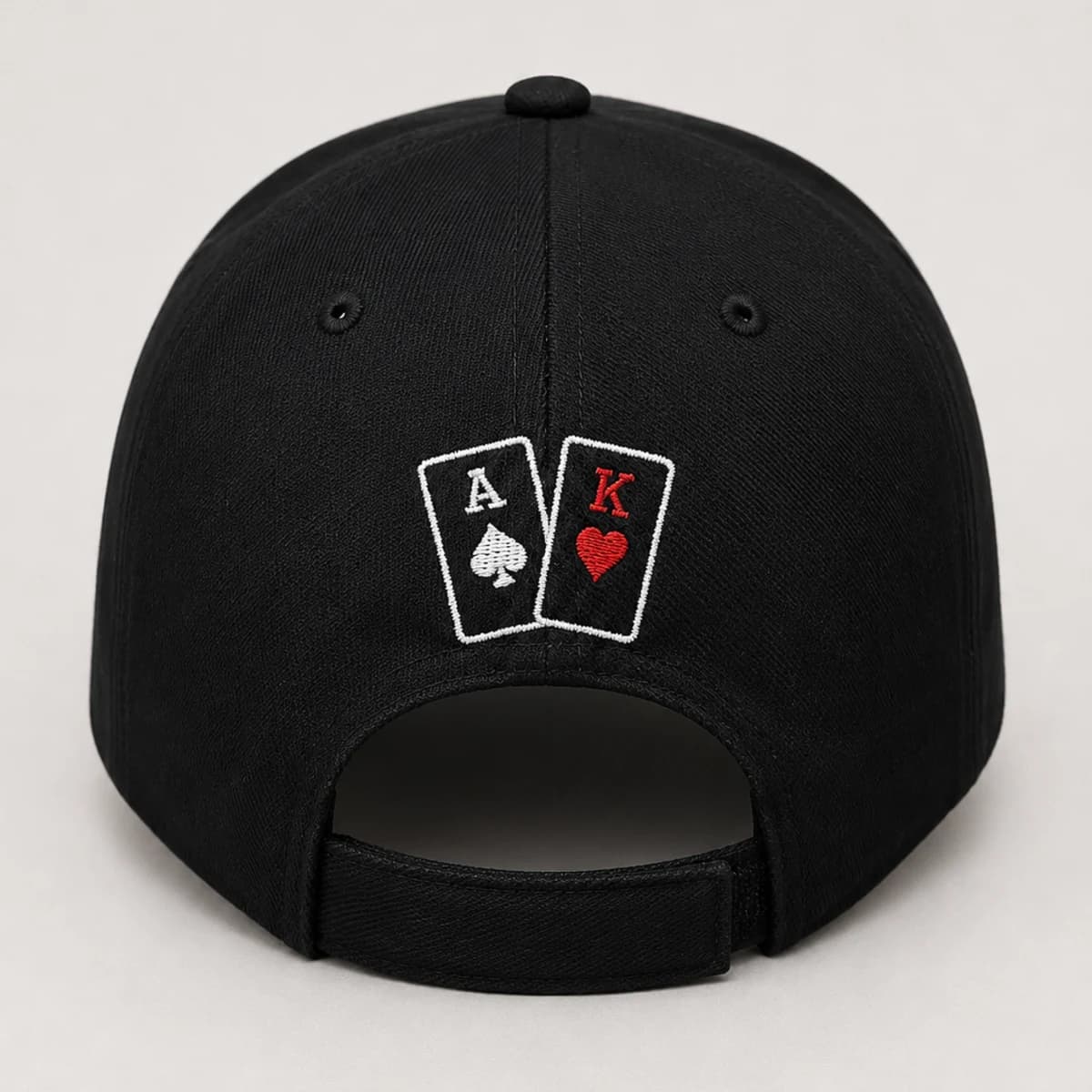 Arrière d'une casquette noire avec les cartes As et Roi brodées au-dessus de la sangle